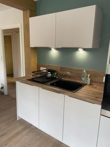 a kitchen with white cabinets and a sink at Chalet Le Cèdre Bleu 10 p - 10 min de Gérardmer in Le Tholy