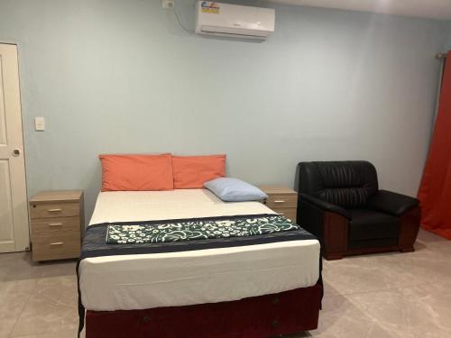 a small bedroom with a bed and a chair at Marine Apartments in Honiara
