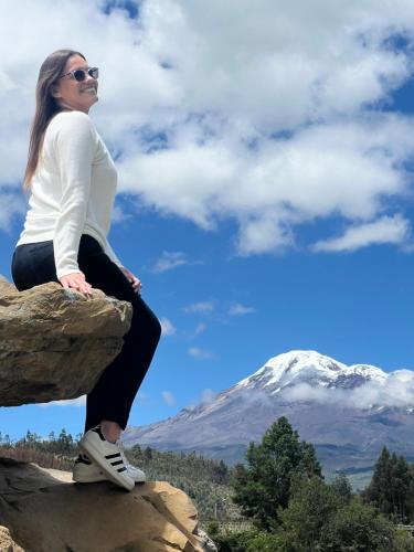 una mujer sentada en una roca con una montaña en el fondo en Steingarten, Casa de Campo hermosa y amoblada., en Riobamba