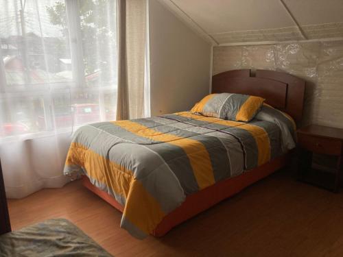 een bed in een kamer met een raam en een bed sidx sidx sidx bij hospedaje 12 de octubre in Coihaique
