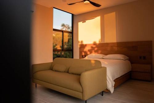 a bedroom with a bed and a couch and a window at Casa Amelia Puerto Escondido in Puerto Escondido