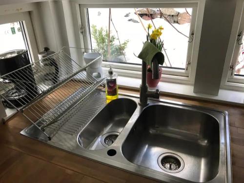 a kitchen sink with a dish rack next to a window at Lilla Gäststugan in Uppsala