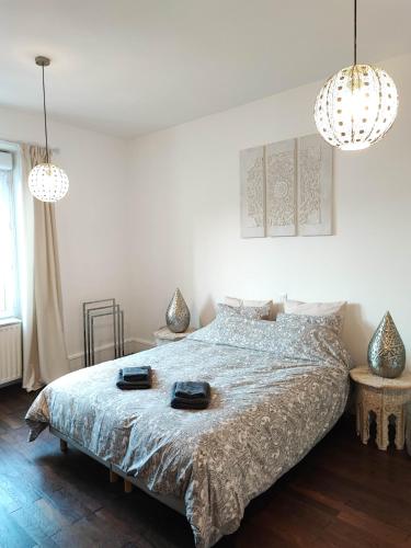 a white bedroom with a bed and two chandeliers at Aux portes de Lyon in Saint-Fons
