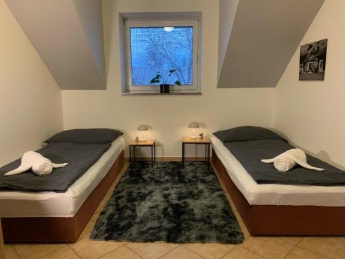 two beds in a room with two tables and a window at Home - Ostružina in Olomouc