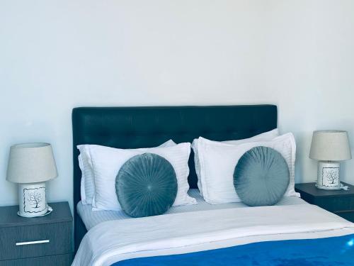 a bed with blue and white pillows and two lamps at Hotel Tamar Mepe in Kutaisi