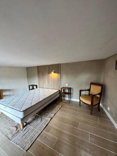 une chambre avec un grand lit et une chaise dans l'établissement Appartement centre village, à Roussillon