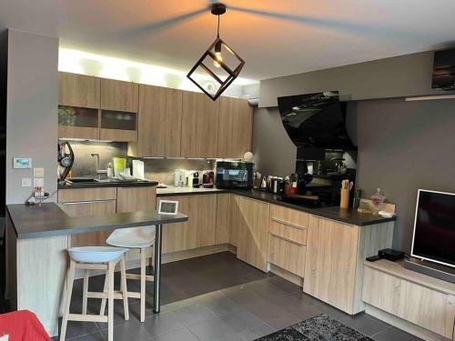 une cuisine avec des placards en bois et un bar avec des tabourets dans l'établissement Coin de détente au centre ville, à Bondy