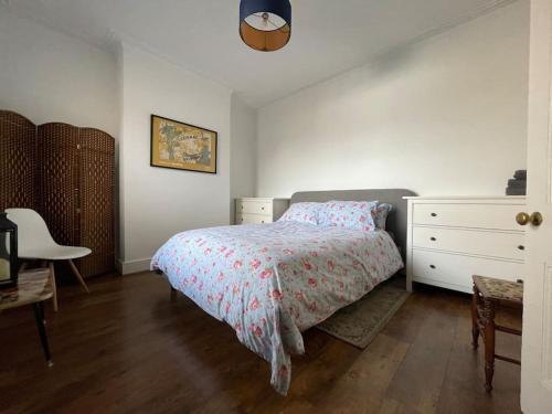 a bedroom with a bed and a dresser and a chair at Stylish, Modern & refurbished flat, 1.5m beach in Southend-on-Sea