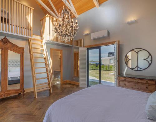 a bedroom with a bed and a chandelier at Beachfront Paradise - Opito Bay Holiday Home in Opito Bay