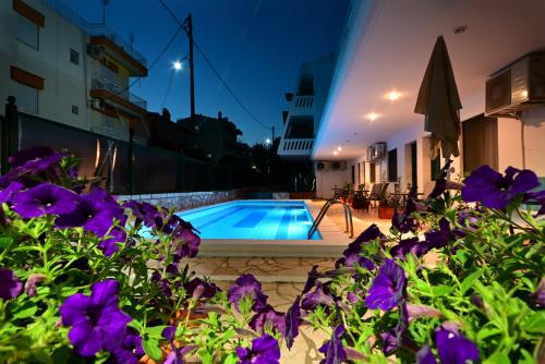 a swimming pool with purple flowers in the foreground at VILLA CARIATIS in Nea Kalikratia