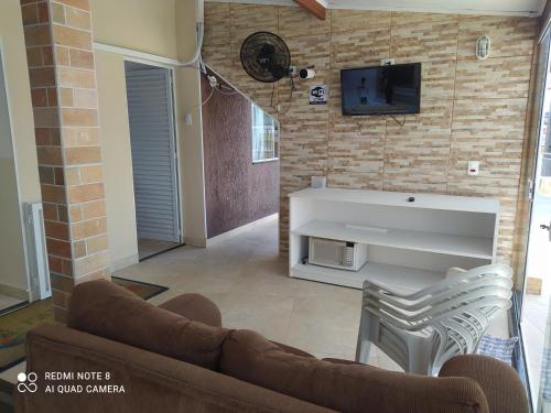 a living room with a couch and a tv on a brick wall at Apartamento familiar in Matinhos