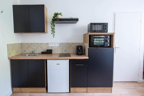 a kitchen with a refrigerator and a microwave at Top Destination Moissac in Moissac