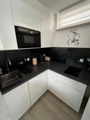 a kitchen with white cabinets and a black counter top at Lilis Apartment mit Balkon in Augsburg
