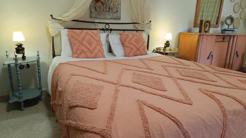 a bedroom with a large pink bed with two lamps at Ancient Corinth Guest House in Kórinthos