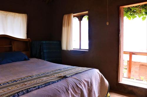 a bedroom with a bed and two windows at BLUE SKY Lodge Taquile in Huillanopampa