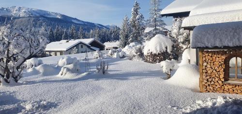 a house covered in snow next to a house at Chalet Weitsee in Reit im Winkl