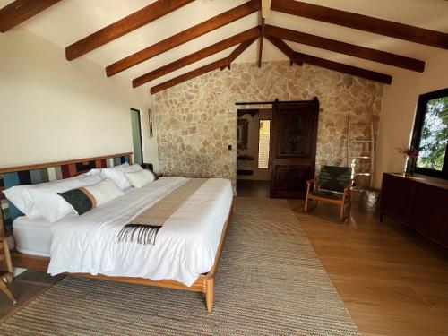 a bedroom with a large bed and a stone wall at Monkey House in Dominicalito