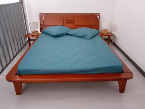 łóżko z drewnianym zagłówkiem i 2 stolikami nocnymi w obiekcie Chambre chez l'habitant "Fleur de canne" w mieście Pointe-à-Pitre