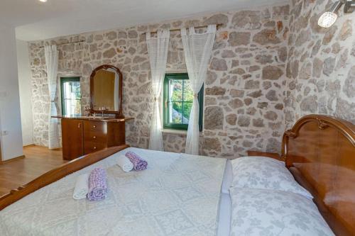 a bedroom with a large bed and a stone wall at Villa Ivana in Zmijavci