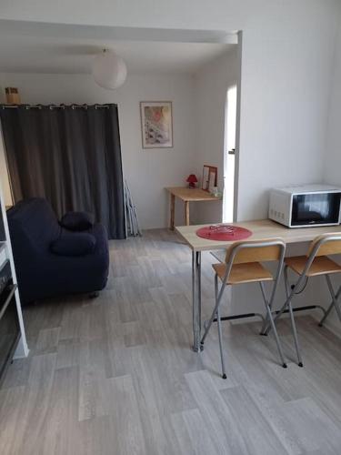 a living room with a table and a microwave at Studio neuf confortable à 10 min à pied de la gare in Nîmes