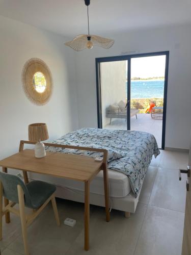 ein Schlafzimmer mit einem Bett und einem Tisch und einem Fenster in der Unterkunft Le Galatee -T2 luxe les pieds dans l'eau - Porticcio in Porticcio