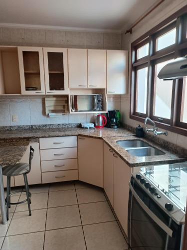 a kitchen with a sink and a stove at Apto grande em Camobi in Santa Maria