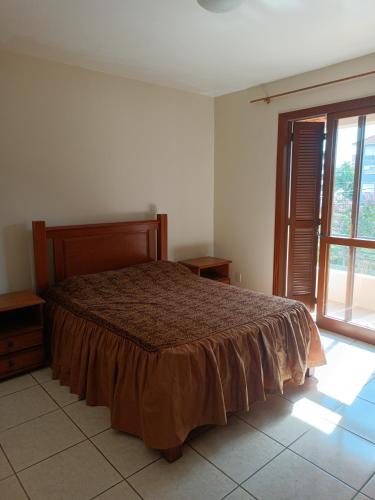 a bedroom with a bed and a large window at Apto grande em Camobi in Santa Maria