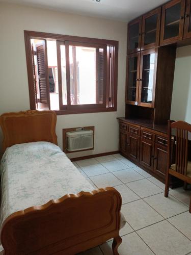 een slaapkamer met een bed, een stoel en ramen bij Apto grande em Camobi in Santa Maria
