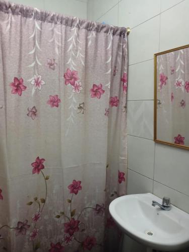 ein Badezimmer mit einem Waschbecken und einem Duschvorhang mit Blumen in der Unterkunft 3 Floor Seawiew in Montañita