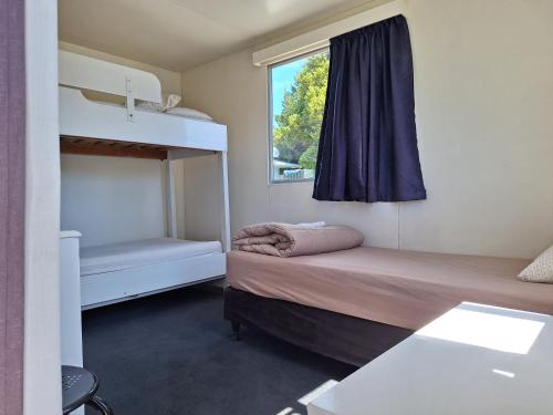 a bedroom with two bunk beds and a window at Picton's Waikawa Bay Holiday Park in Picton