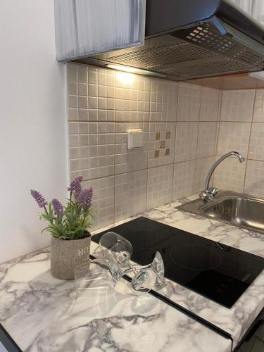 a kitchen counter with a sink and a vase with purple flowers at ARTEMIS beach studios in Kalamaki Heraklion