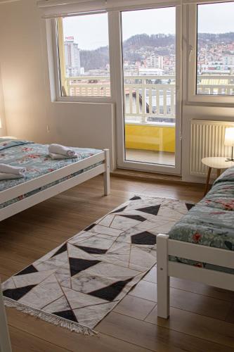 a bedroom with two beds and a large window at Apartment Forever in Tuzla