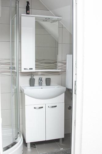 a white bathroom with a sink and a shower at Apartment Forever in Tuzla