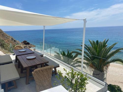 een tafel en stoelen op een balkon met uitzicht op de oceaan bij Sofi Mar - Plomari - The place to be in Plomarion