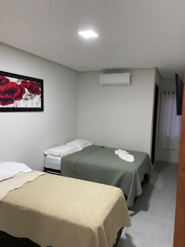 a hotel room with two beds and a painting on the wall at Hotel Eldorado in Maracás