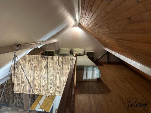 a attic bedroom with a bed and a wooden ceiling at La Grange in Carentan