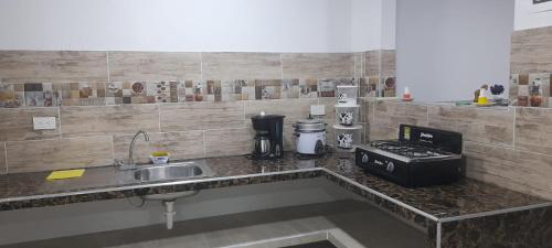 a kitchen with a sink and a counter top at Apartahotel Zamflor in Puerto Asís
