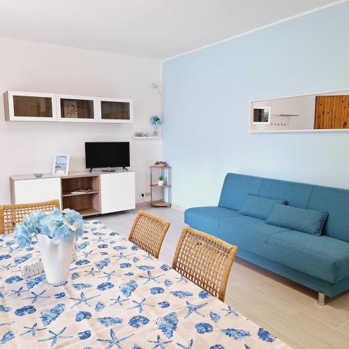 - un salon avec un canapé bleu et une table dans l'établissement Conero Casa Vacanze Amelia Garden, à Numana