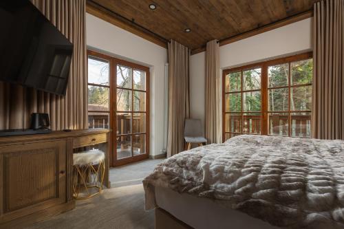 Schlafzimmer mit einem Bett, einem Schreibtisch und Fenstern in der Unterkunft Chalet Royal in Sinaia