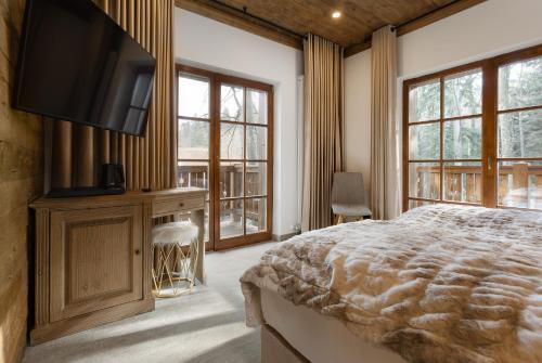 a bedroom with a bed and a tv and windows at Chalet Royal in Sinaia