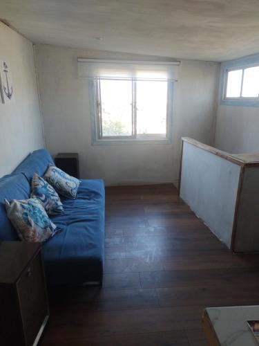 a living room with a blue couch and two windows at Cabaña marinera in Coquimbo