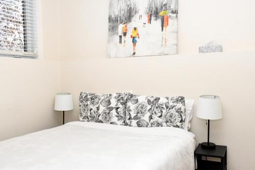 a white bedroom with a bed and two lamps at condo sainte-anne in Beaupré