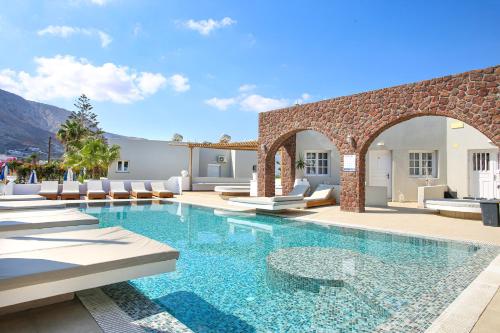 a swimming pool with chairs and a villa at Dimitris Villa in Kamari