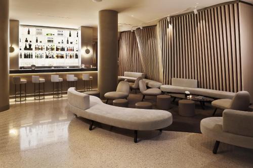 a lobby with a bar with couches and chairs at ME Milan Il Duca in Milan