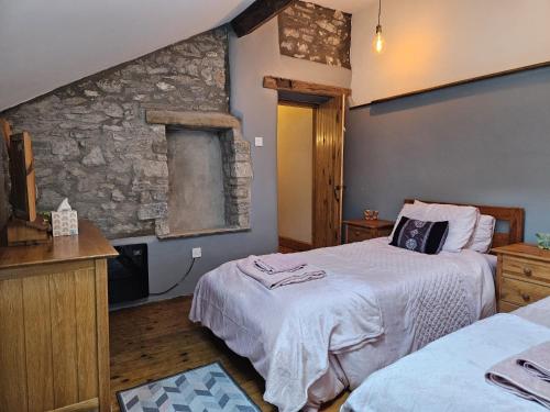 - une chambre avec 2 lits et un mur en pierre dans l'établissement Rose Cottage - Cosy cottage in Millers Dale, à Buxton
