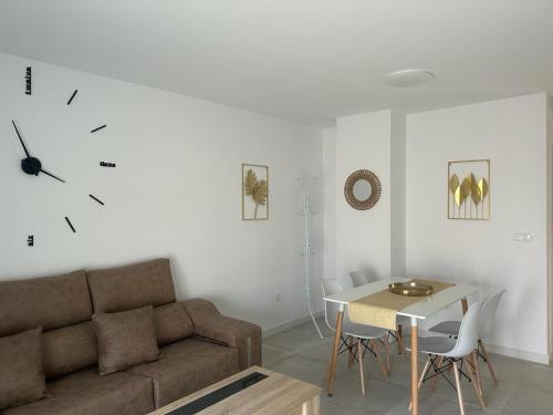 sala de estar con sofá, mesa y reloj en Apartamentos MILANO, en Roquetas de Mar