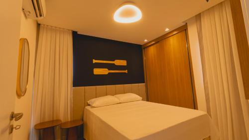 a small room with a bed and a sign on the wall at Flat centro Porto de galinhas in Porto De Galinhas