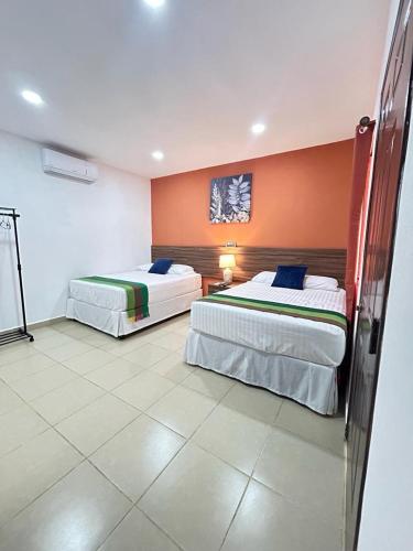 two beds in a hotel room with orange walls at Hotel Boutique Victoria in Moyogalpa