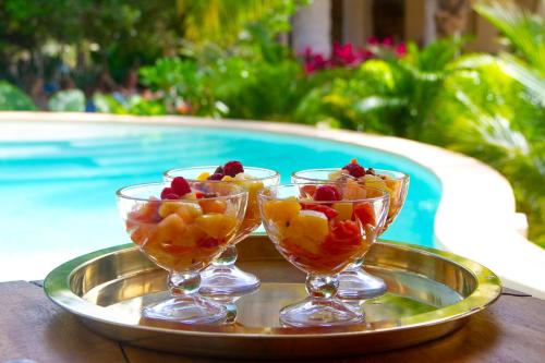 dois copos de frutas em uma bandeja ao lado de uma piscina em Casa Noma-Noma Holbox em Ilha Holbox