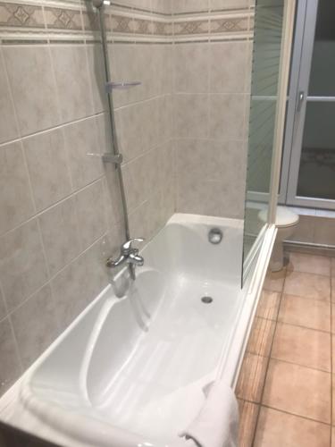 a bathroom with a shower and a white bath tub at Hotel Couleurs Sud Centre-ville Gare Charleville-Mézières in Charleville-Mézières